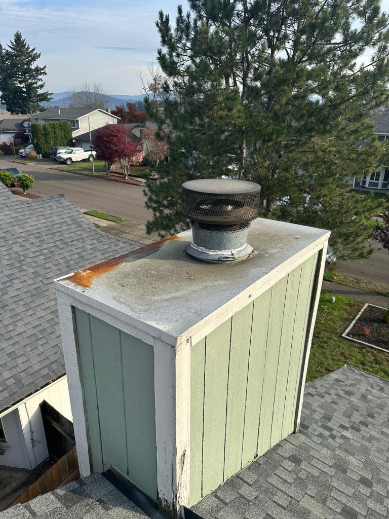 Before: rusted chase cover on a wood-sided chimney chase in Portland, Oregon